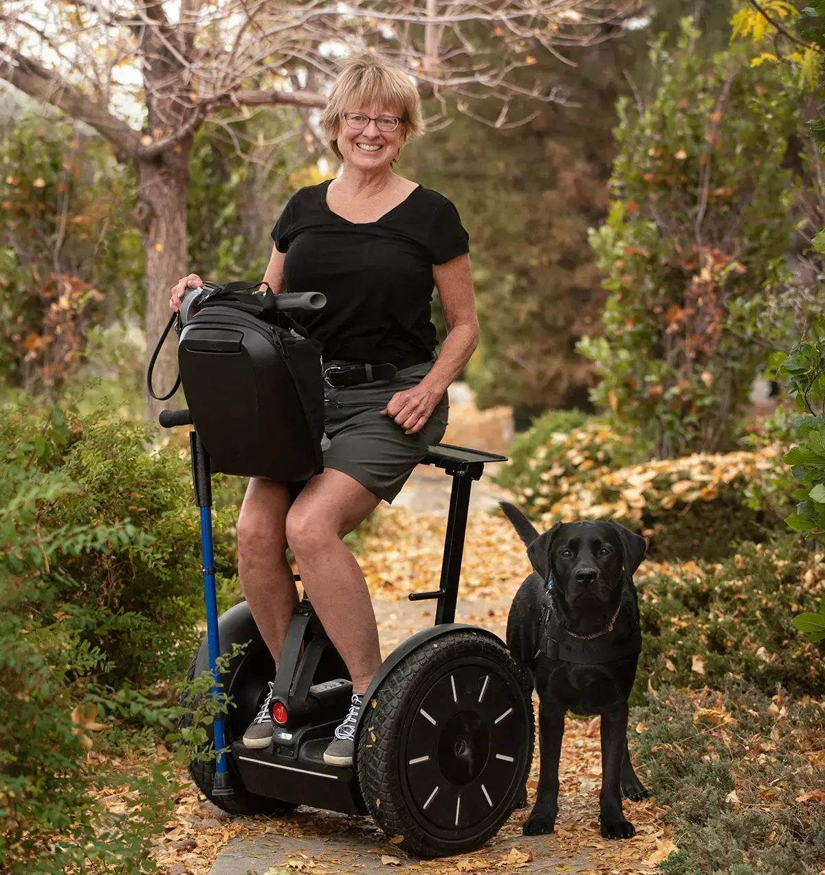 Blonde woman in mobility chair with her black lab service dog