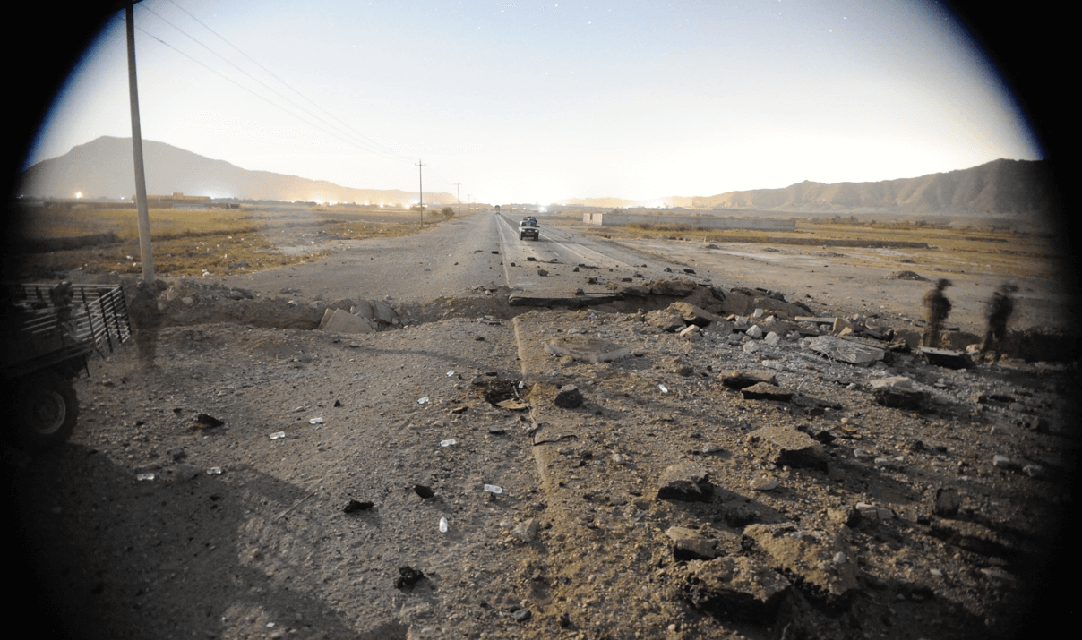 A road in Afghanistan that has been cracked with rubble alongside it due to an explosion.