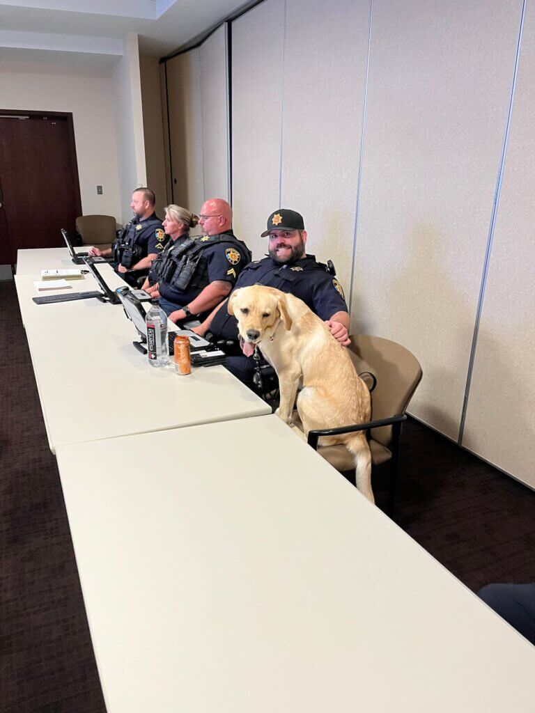 Guster, a yellow Lab, being pet by members of Colorado law enforcement.