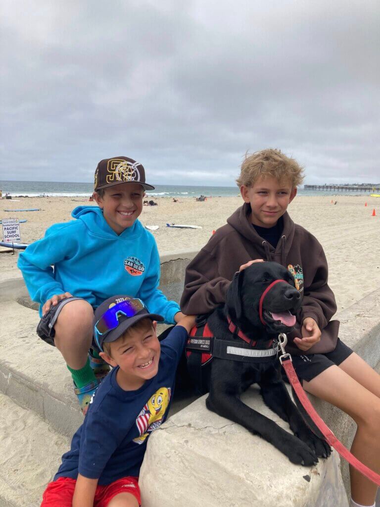 3 kids at the beach with lab puppy