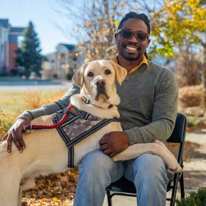 U.S. Army veteran with yellow Labrador wearing army patterned service dog vest.